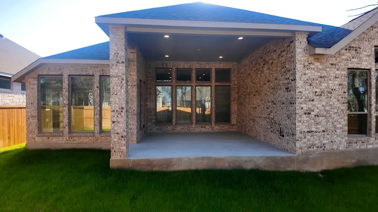 Rear exterior of second home with covered patio fenced yard and trees