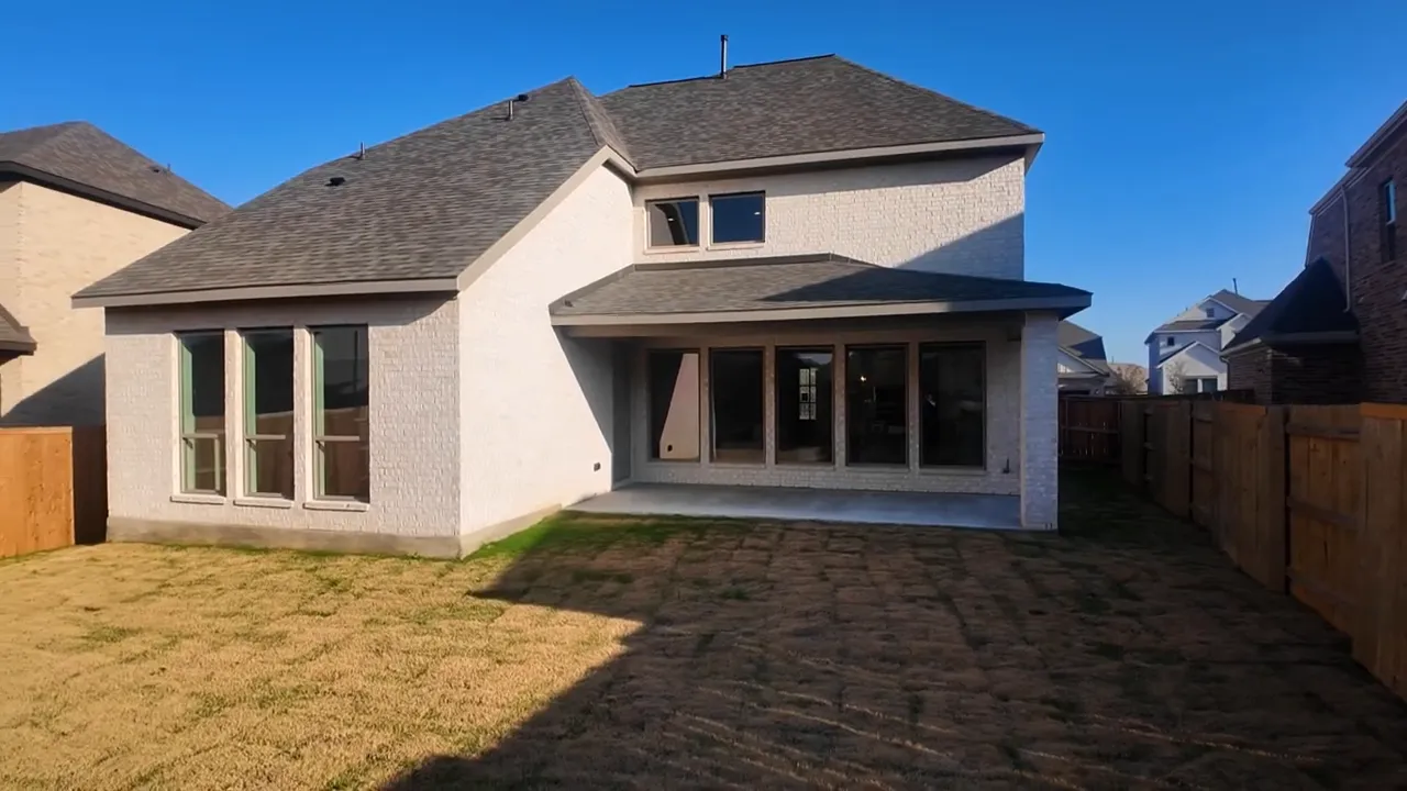Backyard of two story home with covered patio fenced lawn and rear exterior