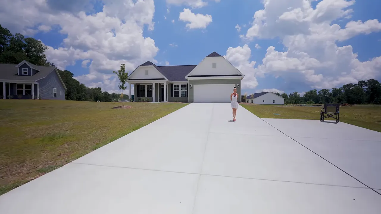 Long concrete driveway with a separate RV pad beside a single-story home