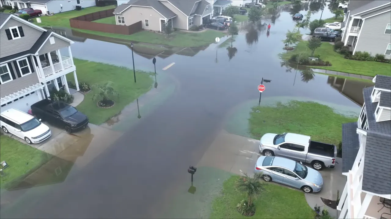Neighborhood street with storm water and sandbags at driveways