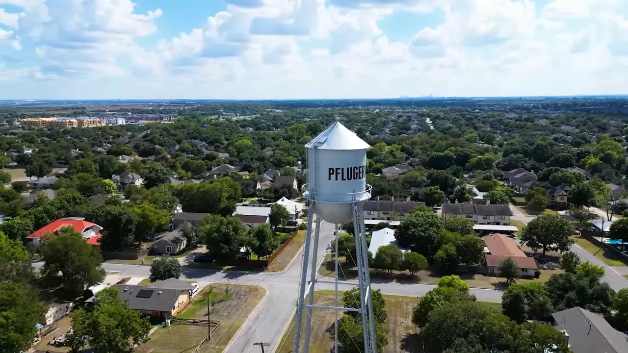 Aerial drone view of the Pflugerville water tower with residential neighborhoods spreading into the distance.