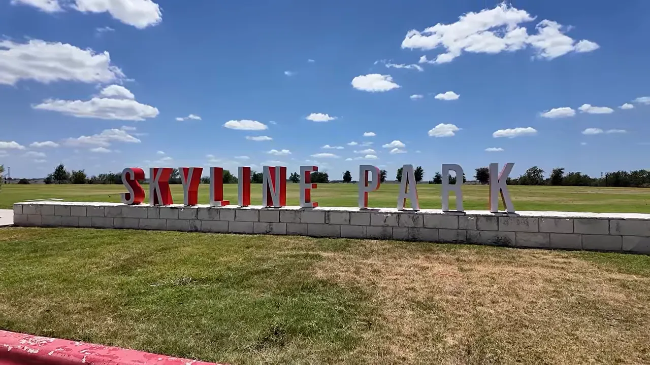 Skyline Park sign beside a sidewalk and open green space