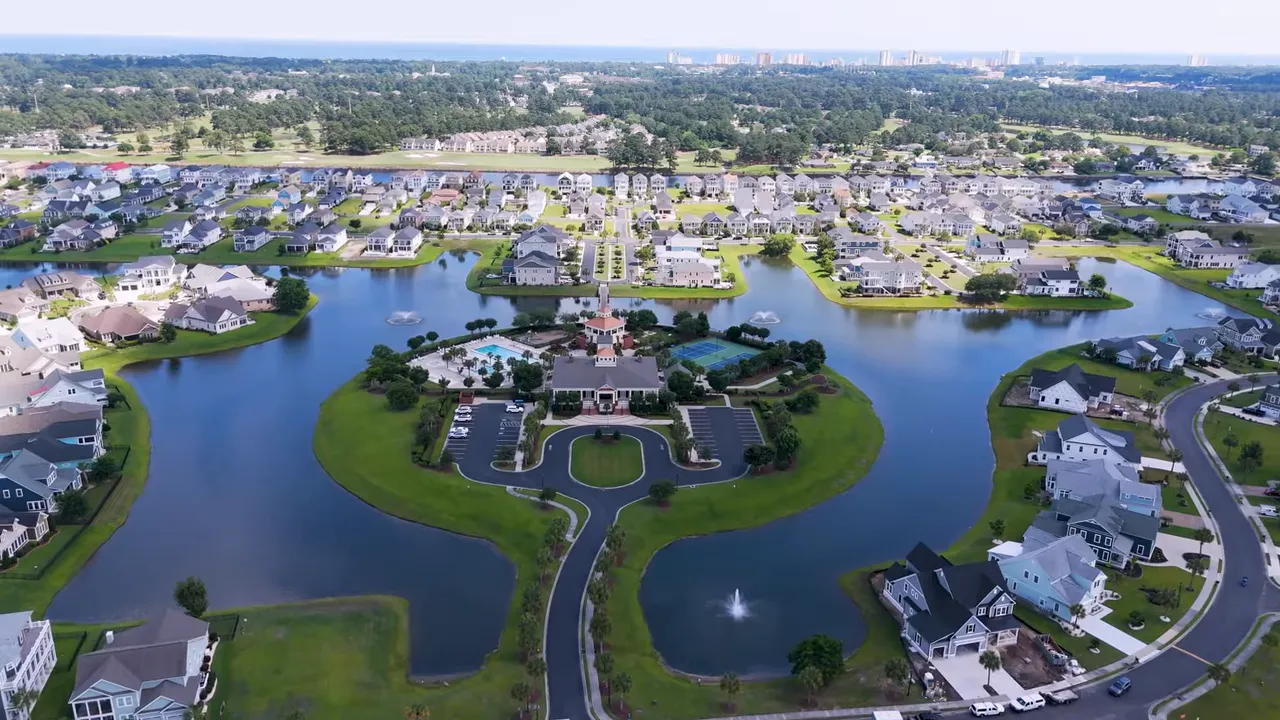 Aerial shot of a master-planned neighborhood with clubhouse, pool, fountains in ponds, and rows of single-family homes.