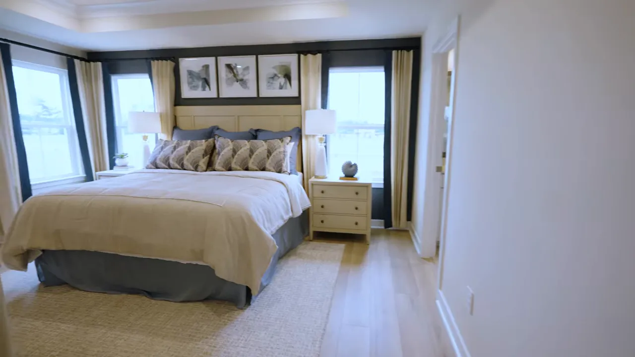 Primary bedroom in a new construction home with bed, side tables, and windows