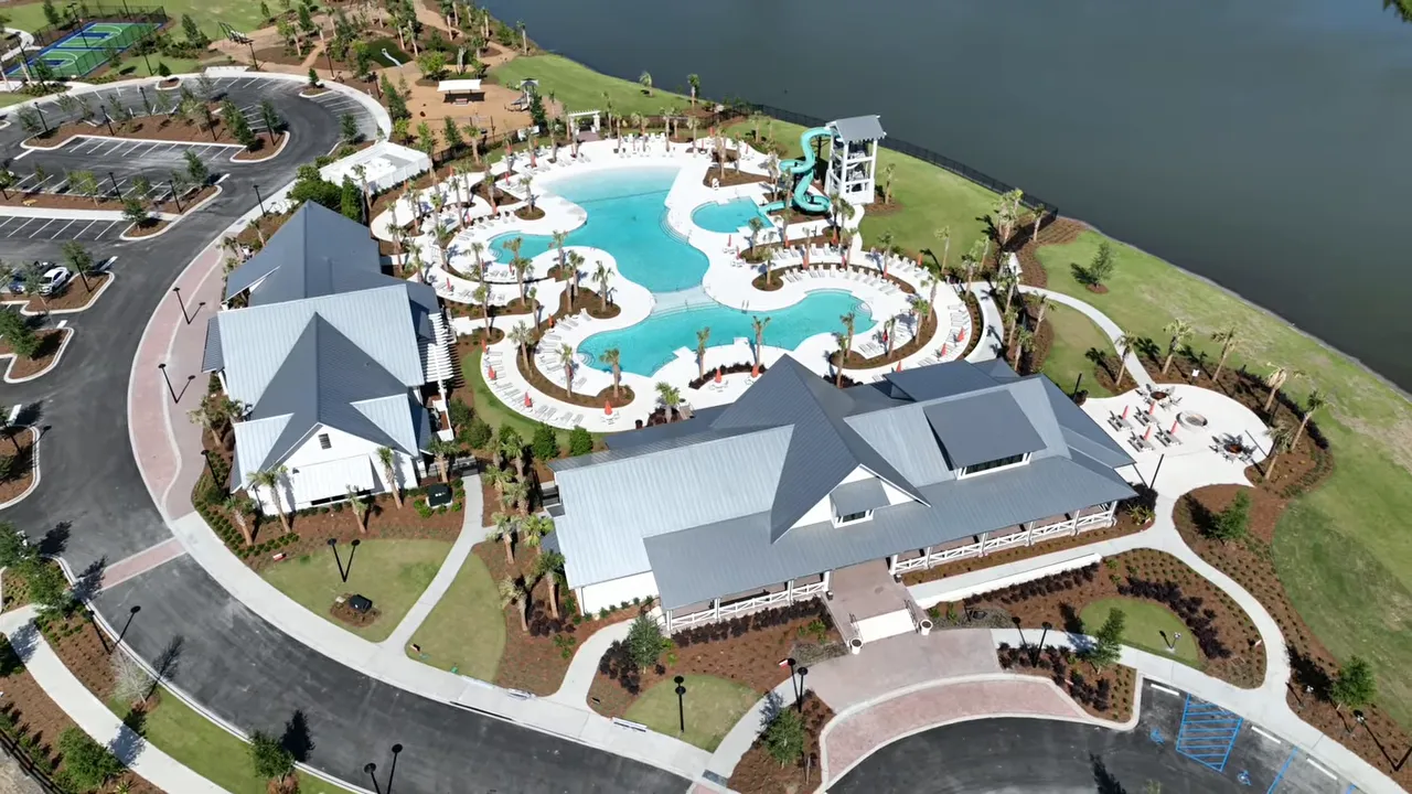 aerial view of a large resort style pool complex beside a lake