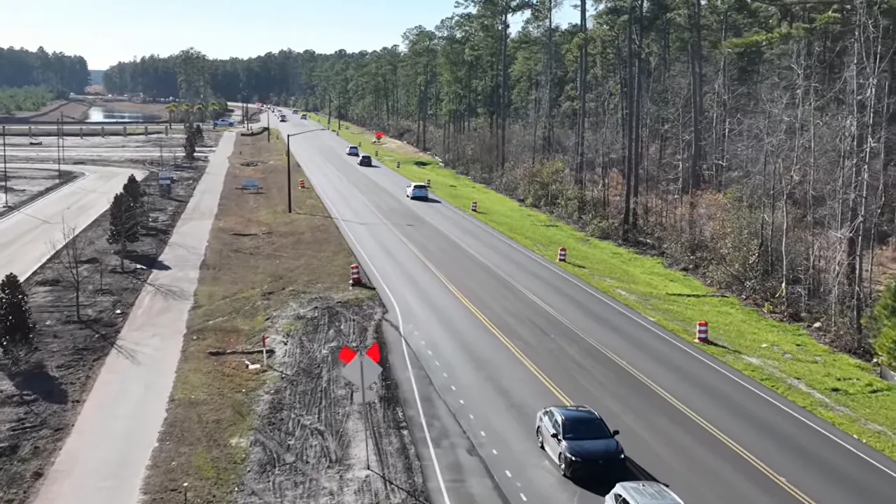 roadway with cars lined up in traffic near a construction corridor