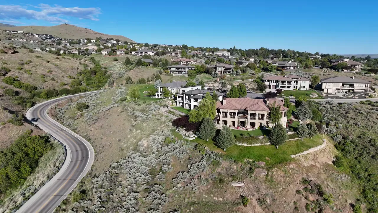 Large homes positioned on a rocky hillside above a curving road