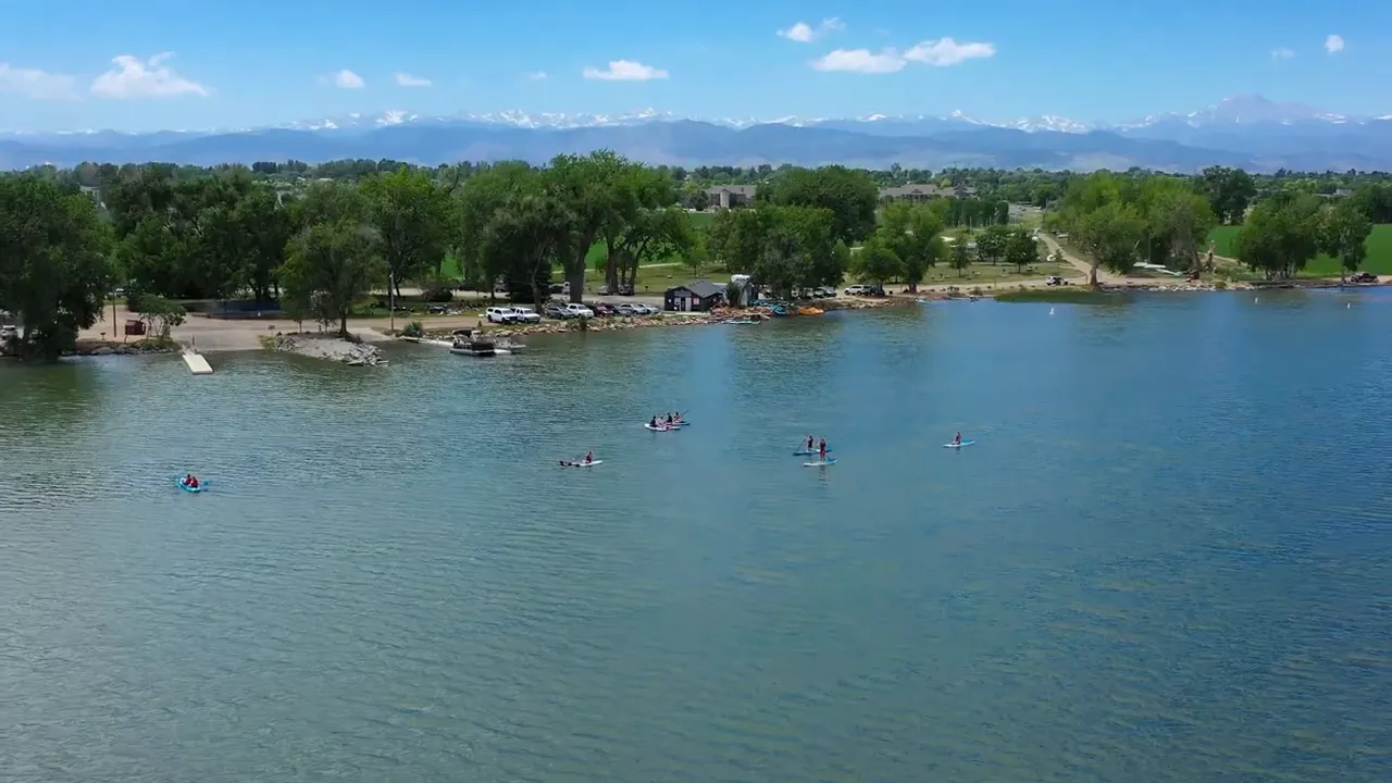Aerial view of a lake with people paddleboarding and a shoreline in the distance