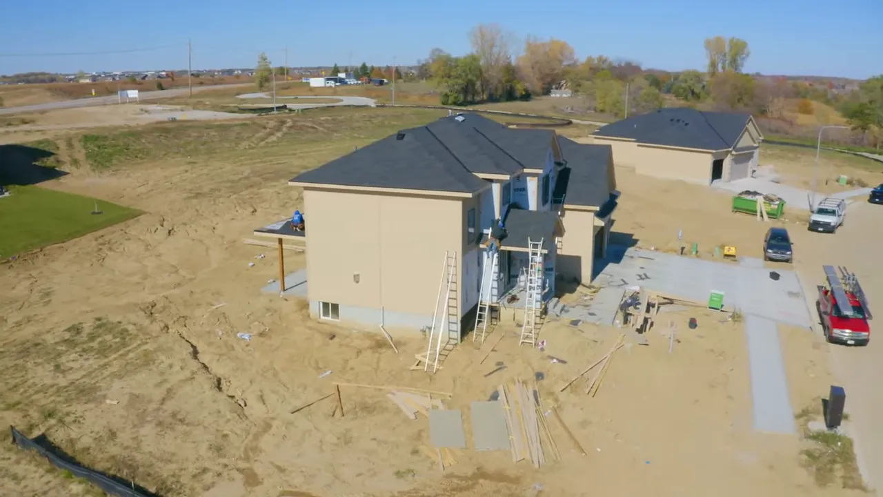 new homes under construction with a telehandler and building materials on a muddy lot