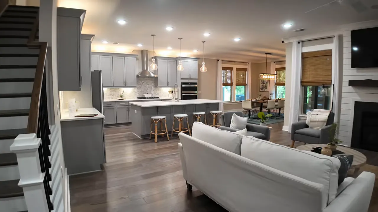 Open kitchen and living room with gray cabinets, large center island, pendant lights and a seating area