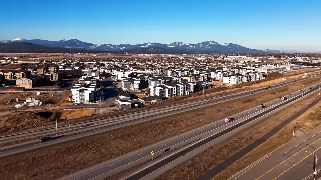 Aerial view of a multi-lane highway running through a city with mountains beyond