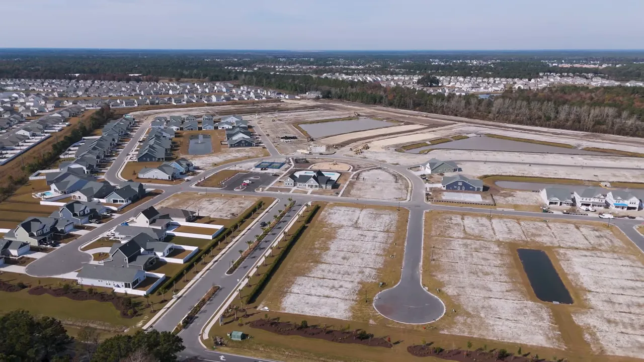 aerial shot of a residential development with finished houses, empty lots and retention ponds