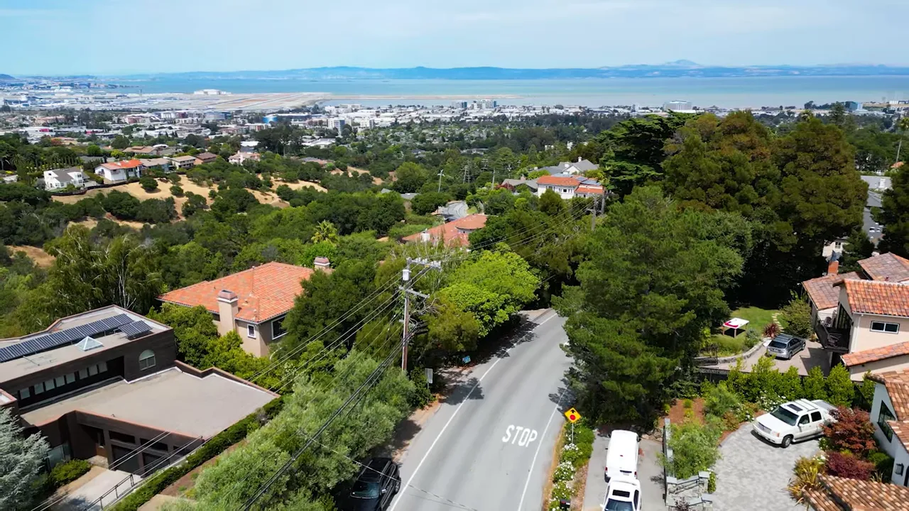 Aerial drone view of a San Mateo County neighborhood with houses, streets and the Bay in the distance