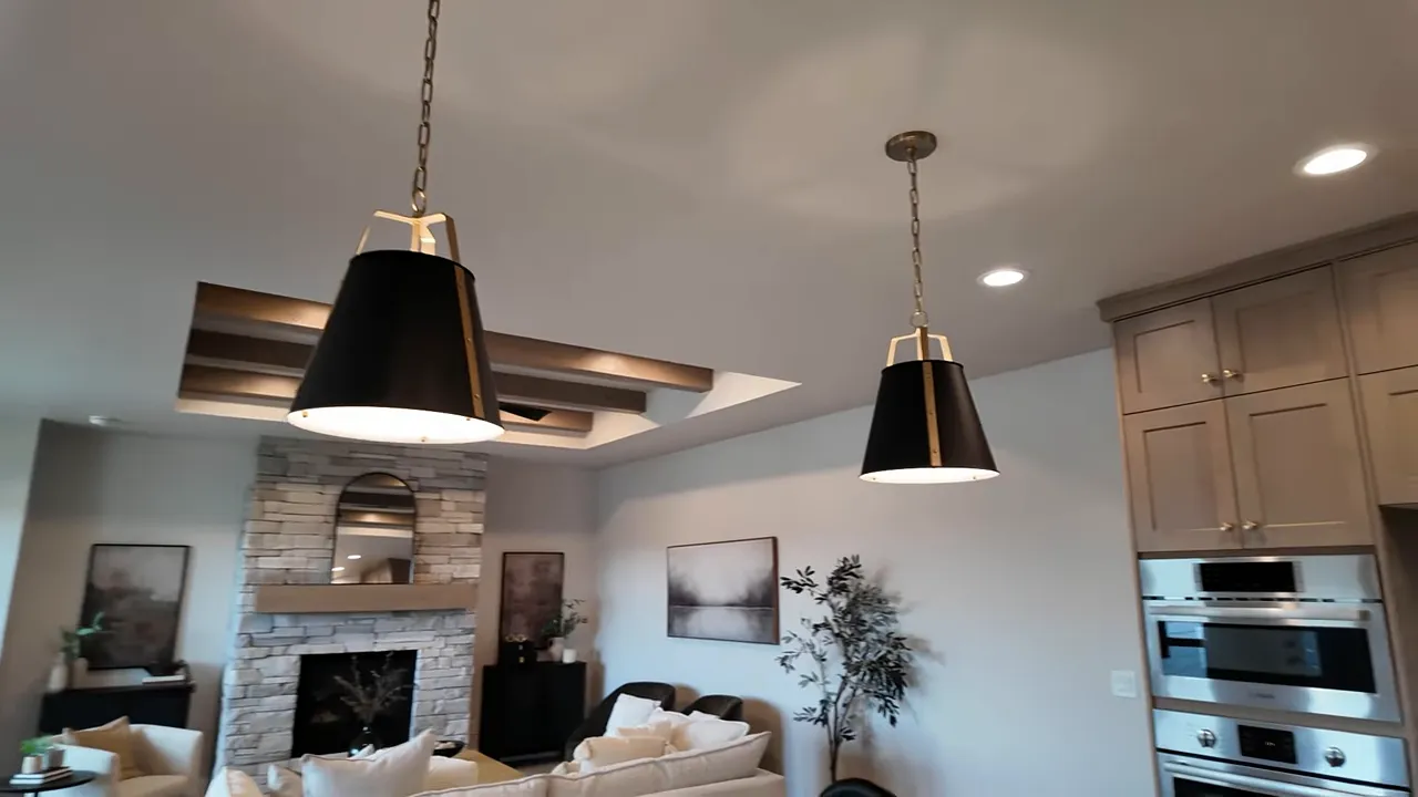 Wide view of open concept kitchen and living room with pendant lights and fireplace