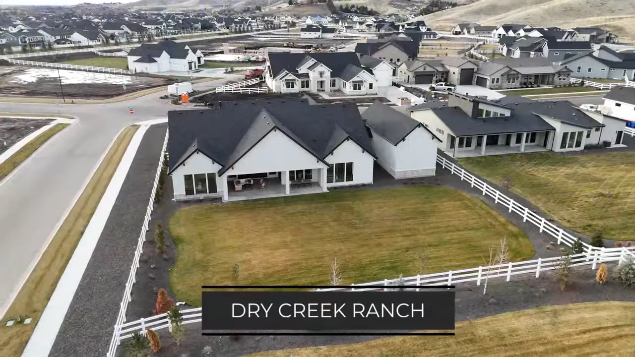 Large white home on a fenced lot within a newer hillside subdivision labeled Dry Creek Ranch