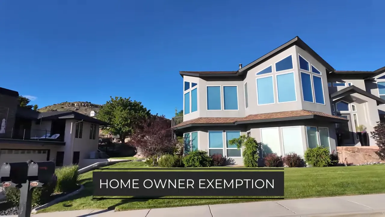 Large upscale home on a hillside street with on screen text about homeowner exemption