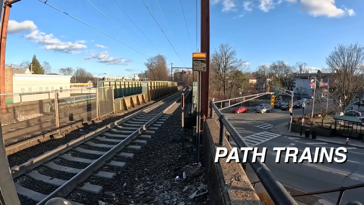 elevated tracks beside roadway with text reading PATH TRAINS