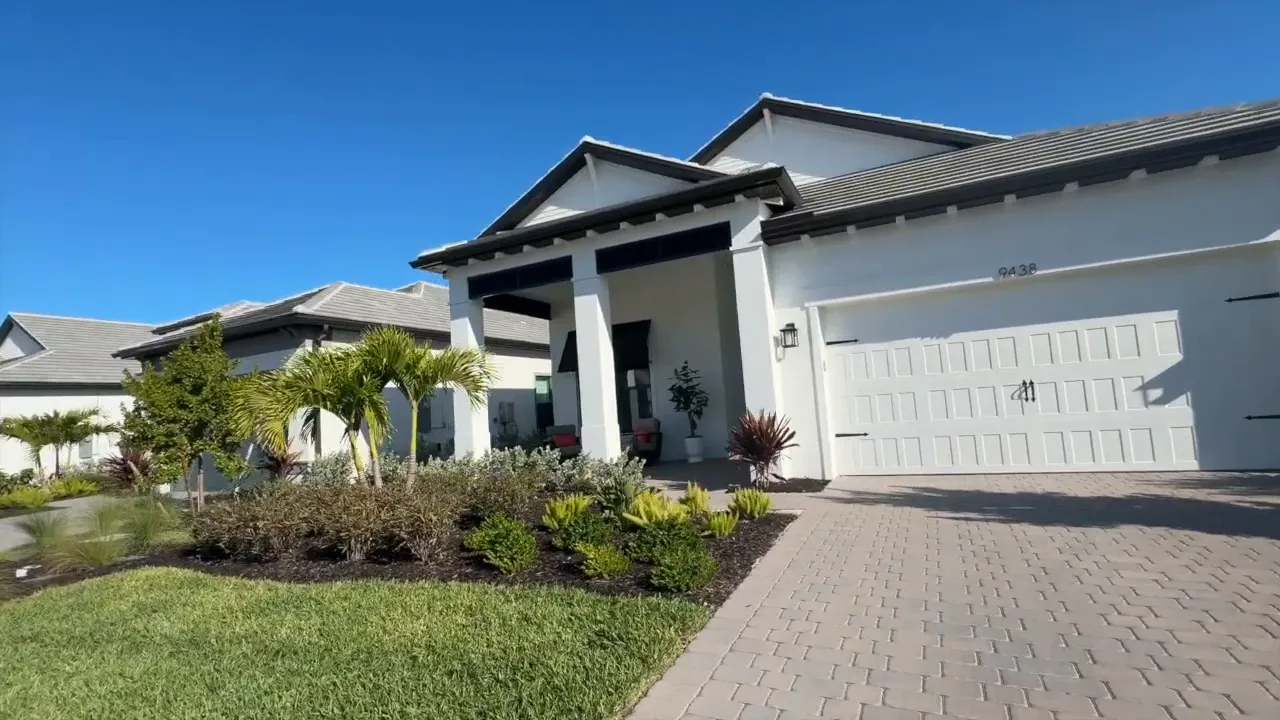White single story home with covered front porch landscaped yard and paver driveway