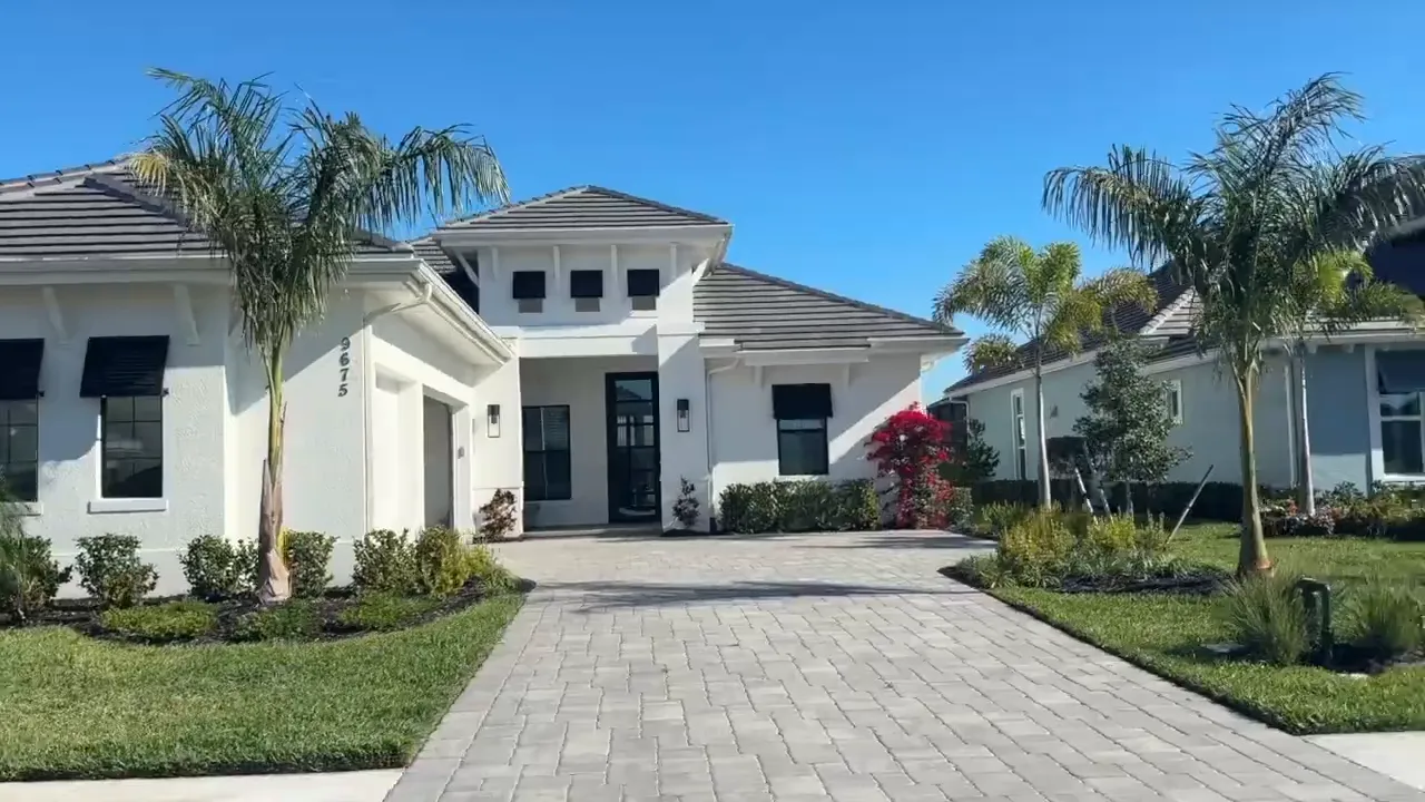 Large white home with paver driveway palms and landscaped front yard