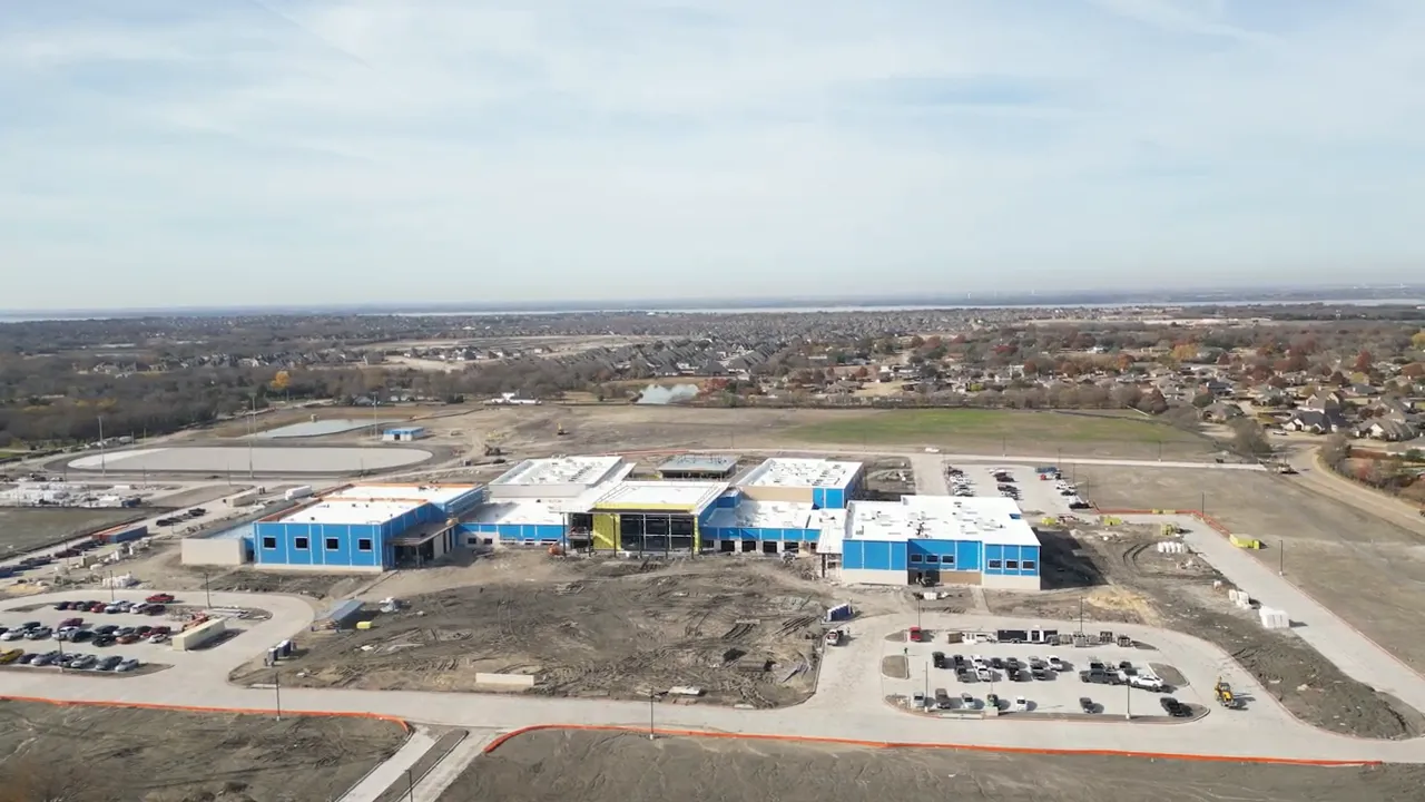 Aerial view of large school campus under construction with parking areas