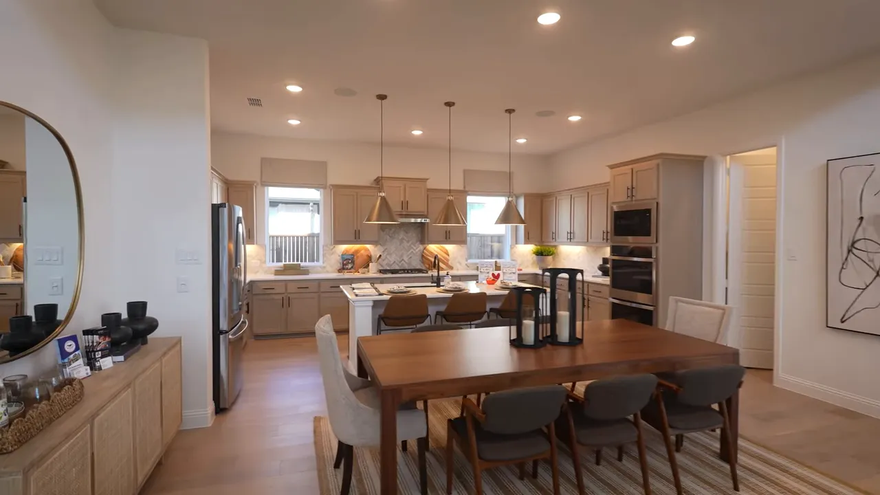 Open kitchen with island, pendant lights, and dining table showing the flow between cooking and living spaces.