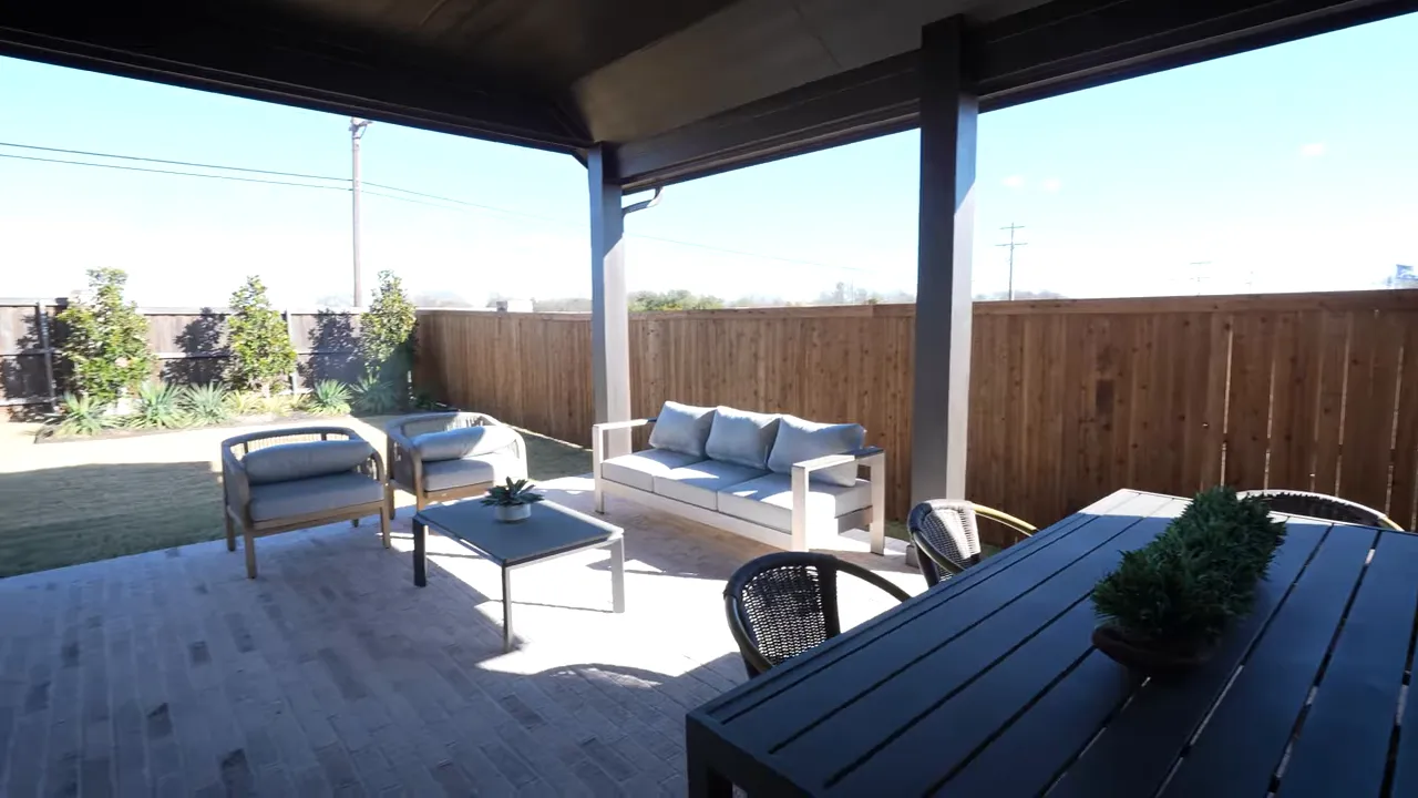 Wide clear view of covered patio with dining table, lounge seating and fenced backyard in Meadow Run