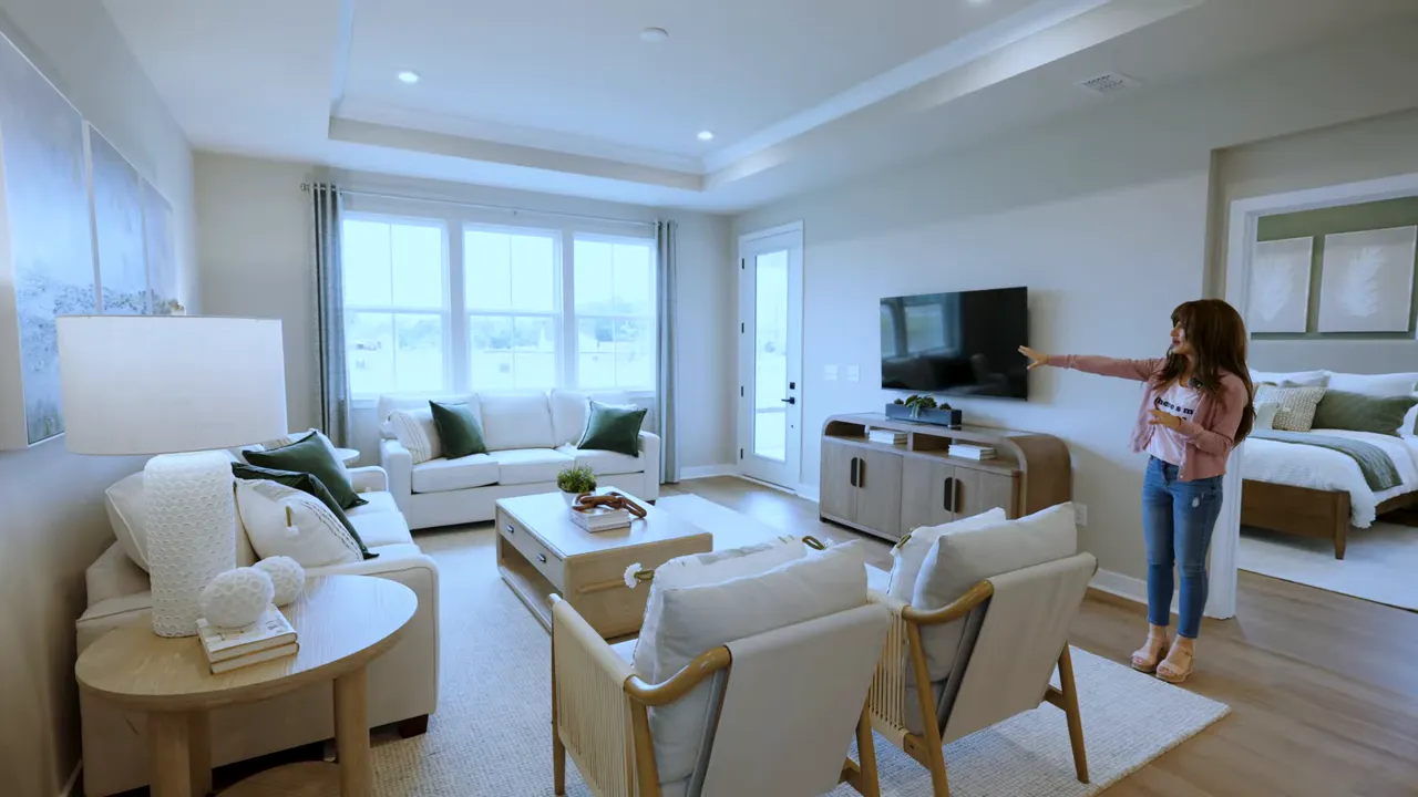 Spacious open living room with sectional seating, coffee table, large windows, and TV stand