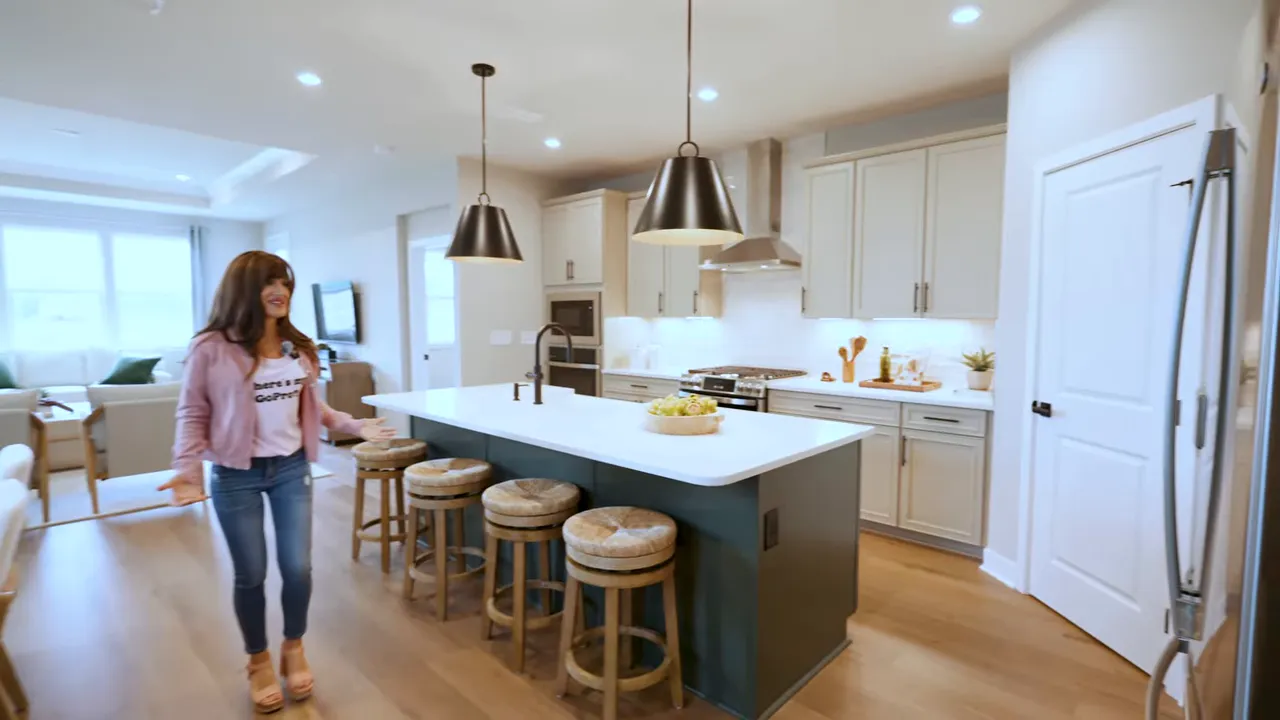 Bright new construction kitchen with gray cabinets, large island with seating, and pendant lighting
