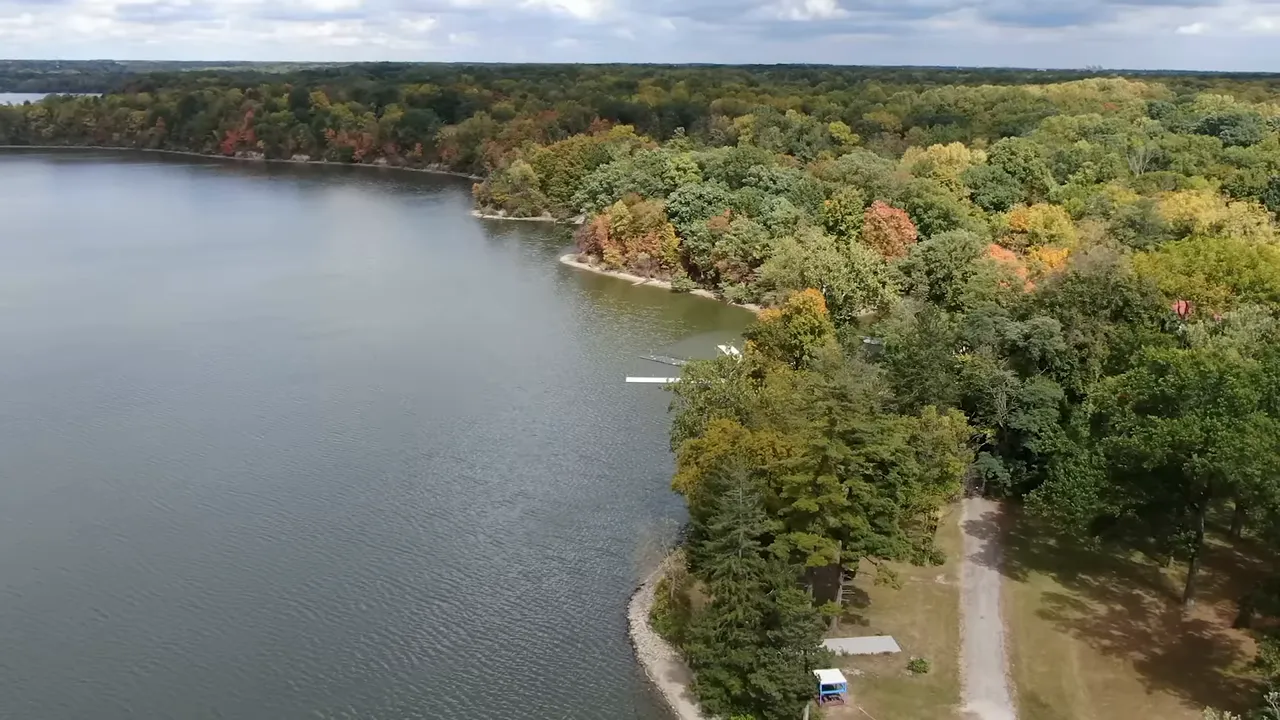 Shoreline, dock and wooded trails at Eagle Creek Park with lake water and autumn foliage