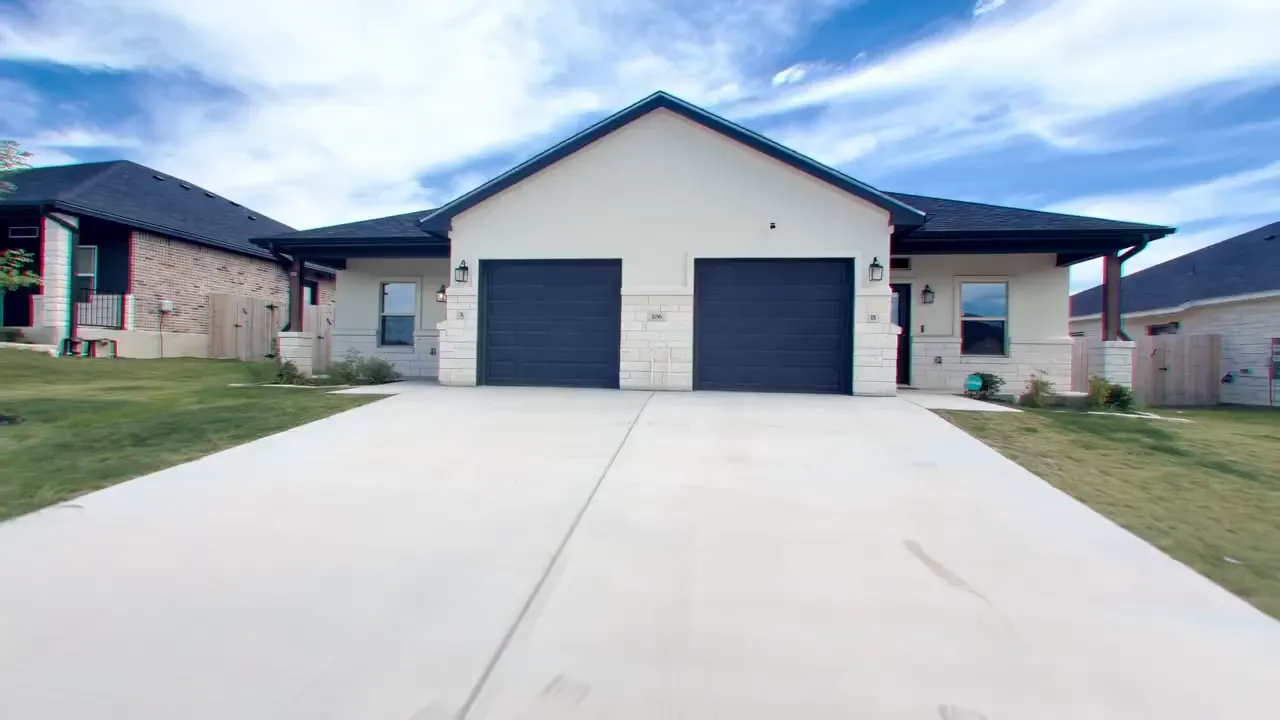 Front exterior of a completed duplex with two garage doors and long driveway