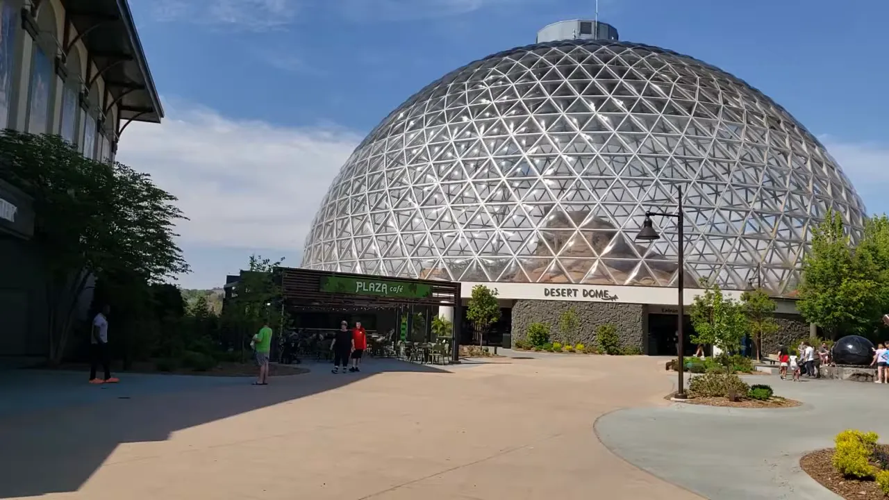Exterior view of the Desert Dome at Henry Doorly Zoo in Omaha, a large geodesic glass dome under a blue sky with the plaza in front.