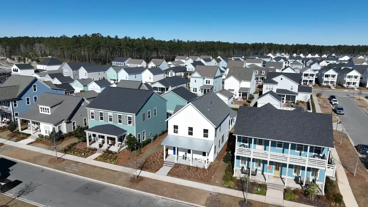 Wide aerial/drone view of a dense new‑build neighborhood showing tightly spaced houses and street layout