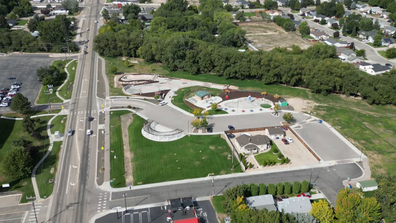 Aerial drone photo of a town showing a park, roads, parking areas and surrounding neighborhood