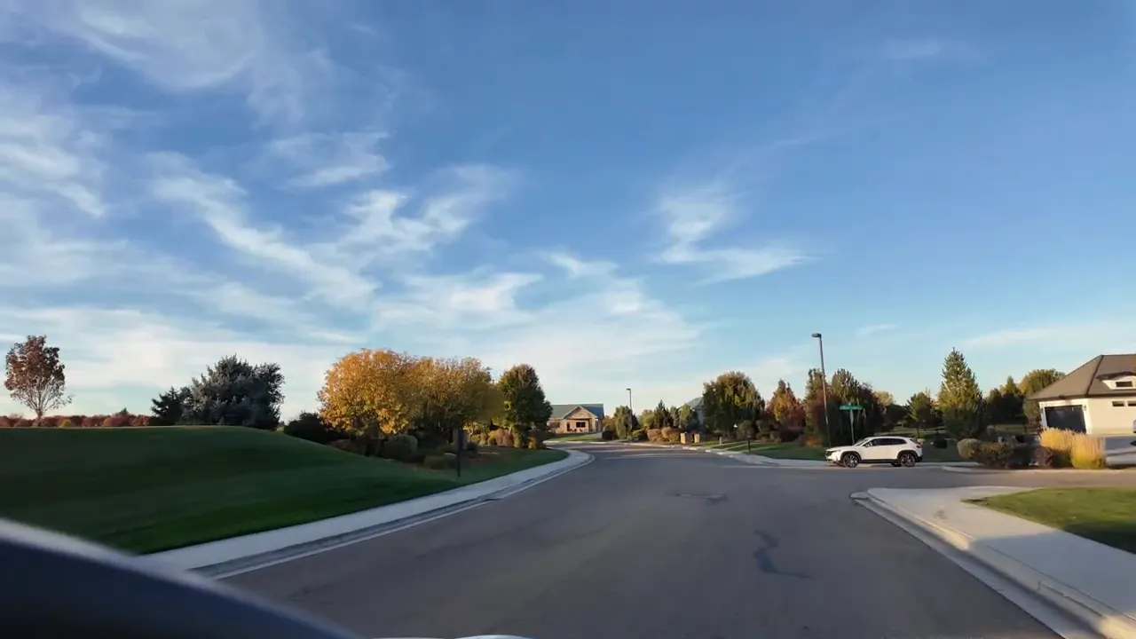 Wide residential street view with autumn landscaping in SpurWing neighborhood near Meridian, Idaho