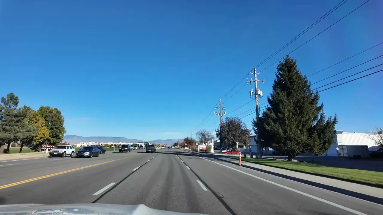 Wide view driving down a main road in Meridian Idaho with businesses, utility poles, and lanes of traffic
