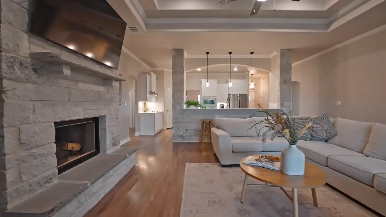 stone fireplace beside a stone-clad bar with view into the kitchen and pendant lighting