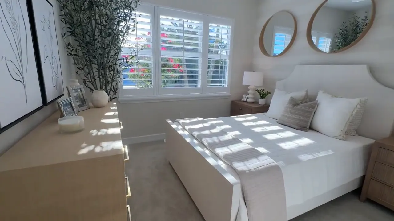Front guest bedroom with bed, nightstands, mirrors, and window shutters