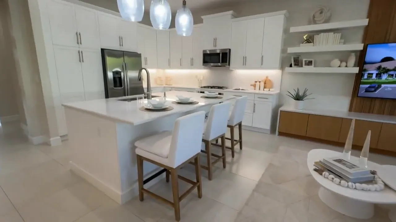 Kitchen island with barstools, sink, white counters, and pendant lights