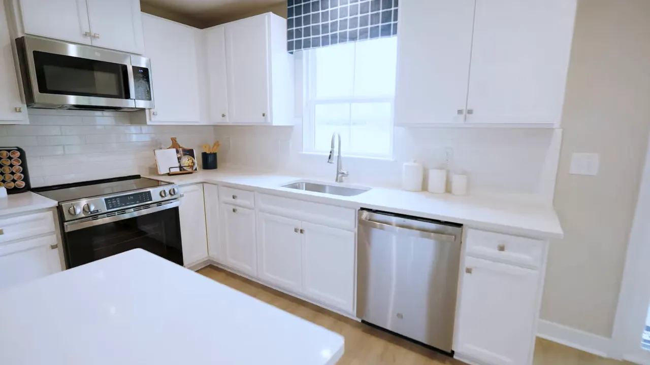 White kitchen with window over sink stainless dishwasher electric range microwave and long counters
