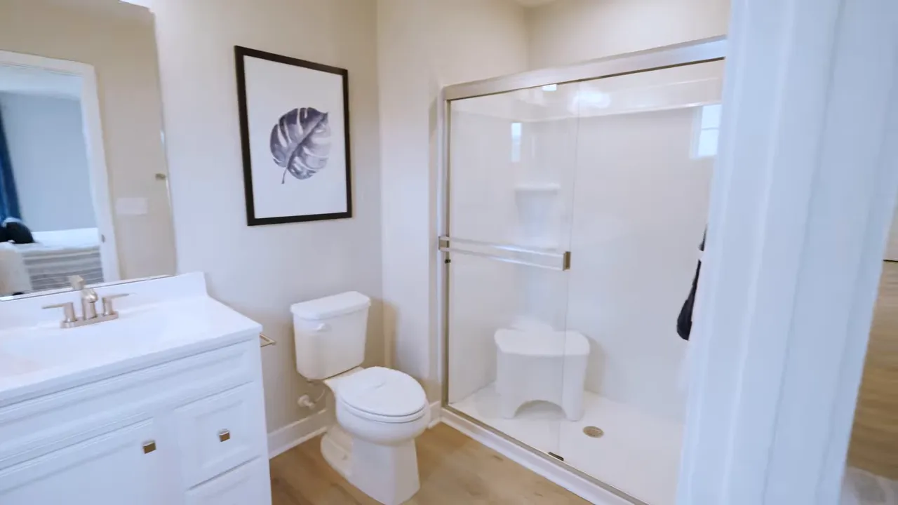 Primary bathroom with white vanity toilet framed shower enclosure and wall art