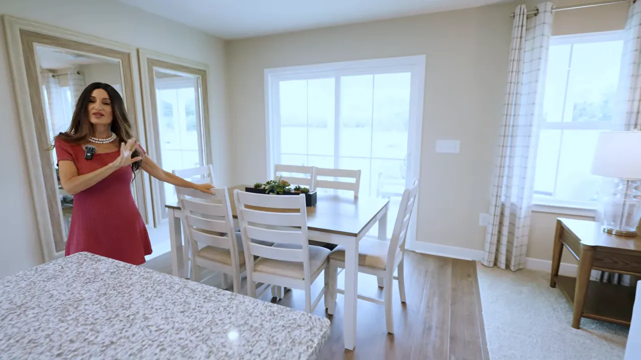 Dining area with six chair table large window and two framed mirrors on the wall