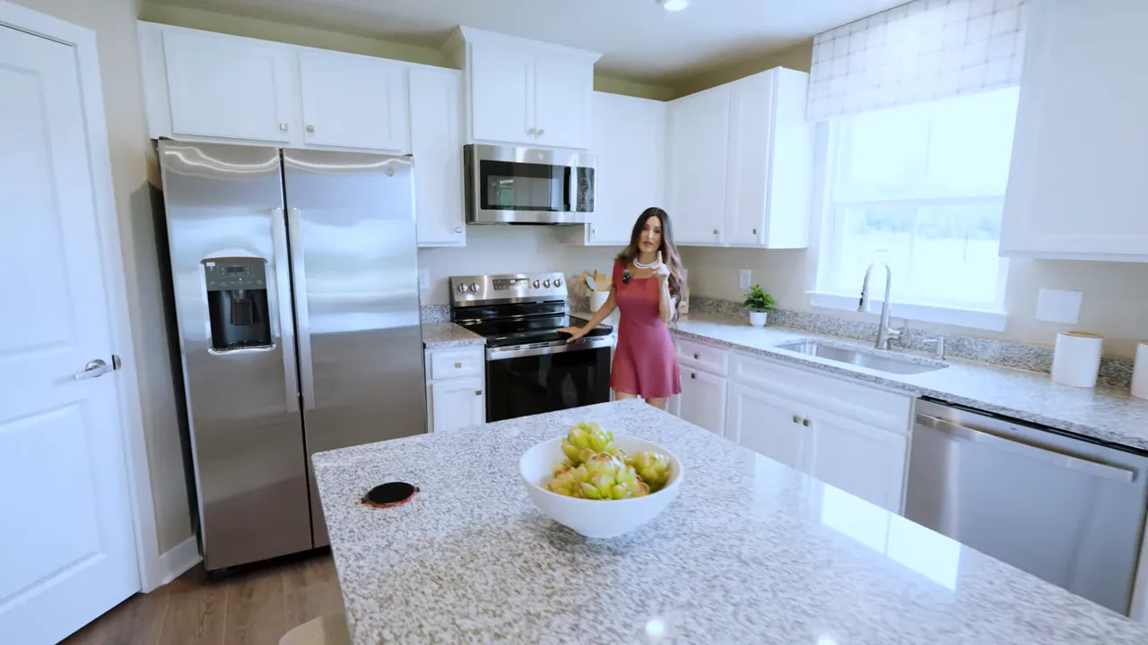 Bright kitchen with speckled island white cabinets stainless appliances and sink under window