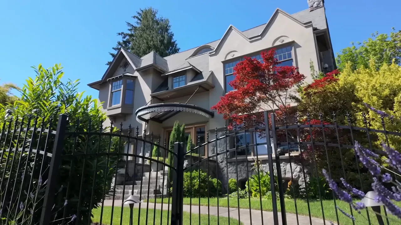 Historic light colored home with front steps and lush garden landscaping