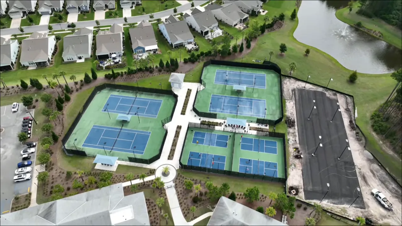Crisp aerial view of multiple pickleball courts at Del Webb Nexton, showing players and a construction area for new courts.