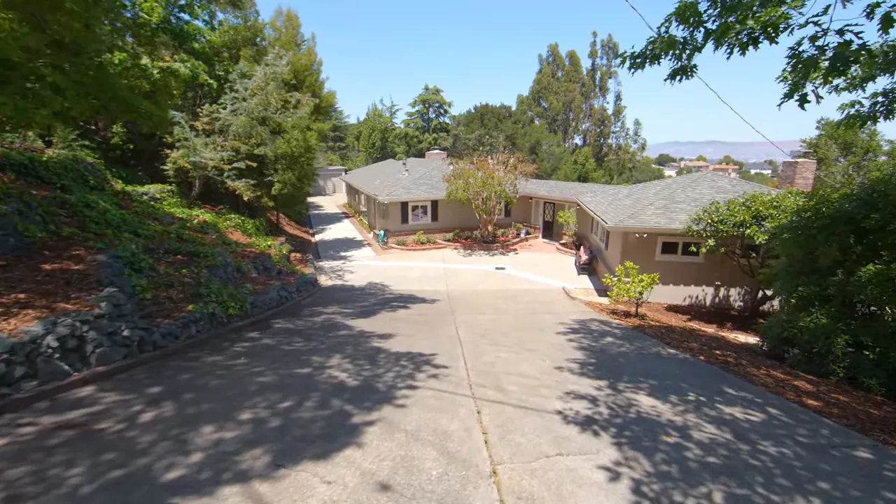 One-level ranch-style home on a large lot with long driveway, mature trees and bay glimpses in the distance