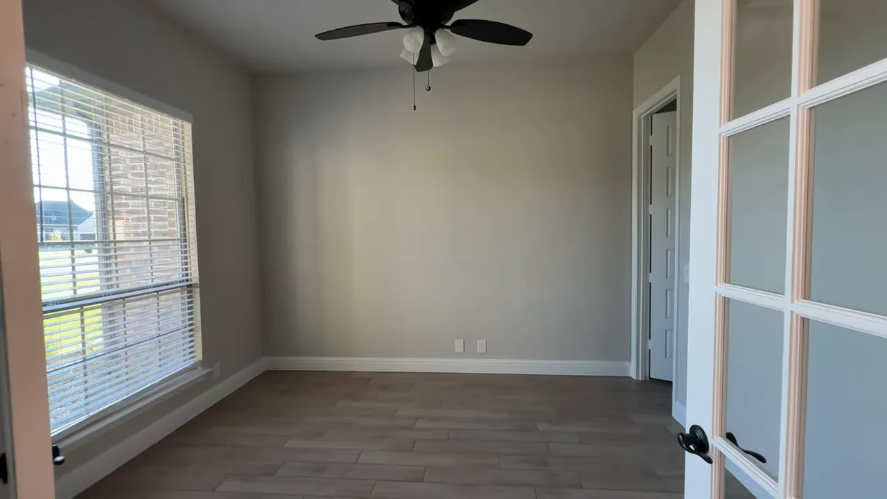 Bright home office with French doors, large front window and ceiling fan in the Castlebury model.