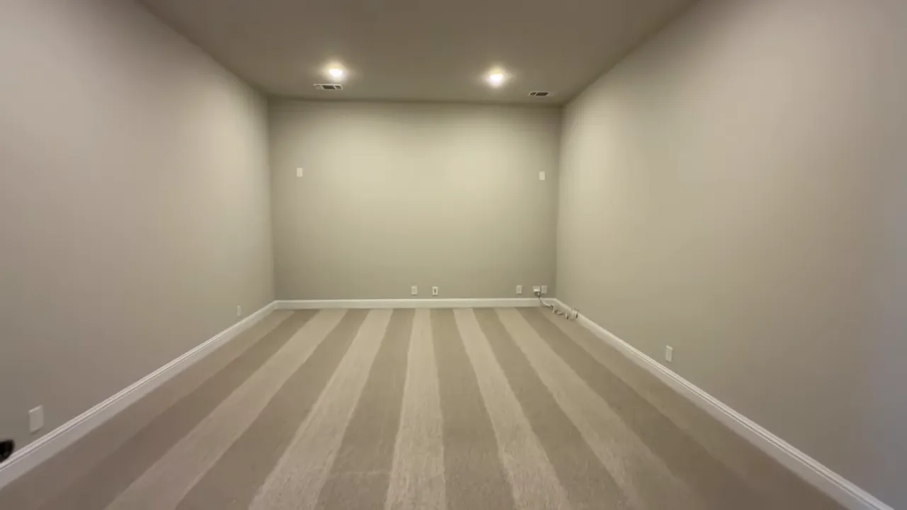 Wide view of a finished media room with recessed lights and striped carpet in the Castlebury floor plan