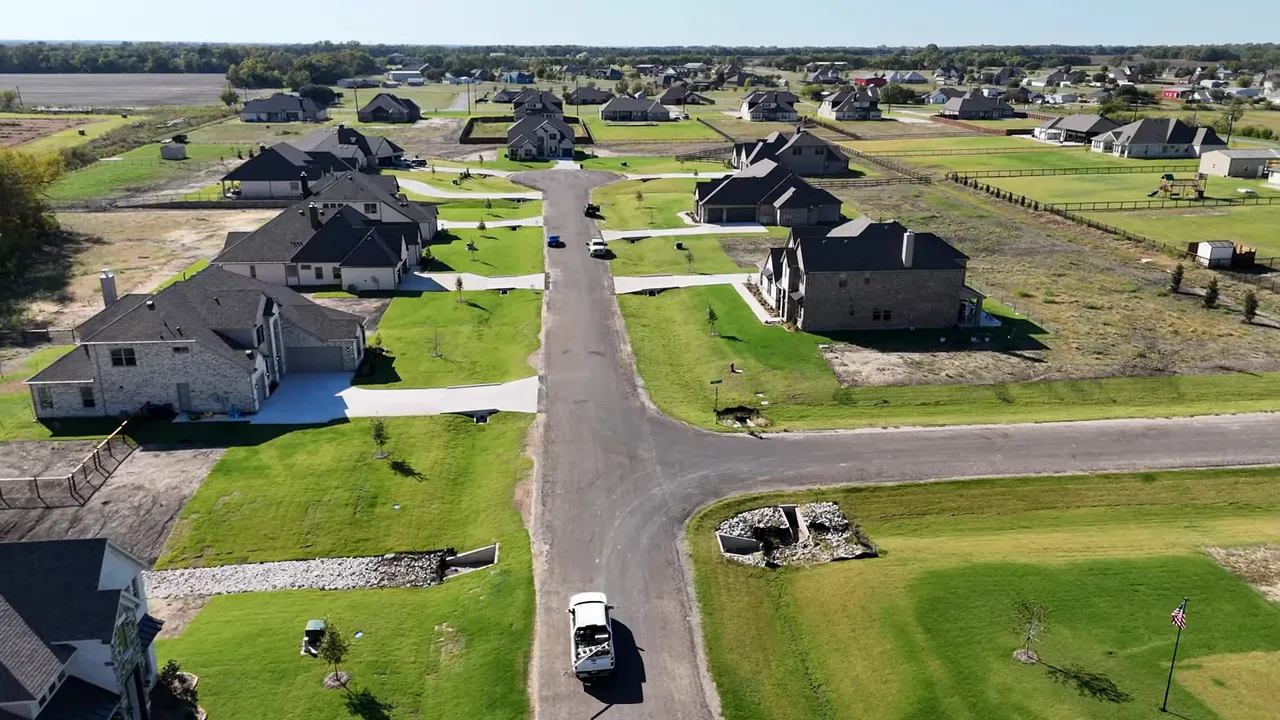 Aerial drone view of a Stonehollow neighborhood showing one-acre lots, green lawns and a quiet street.