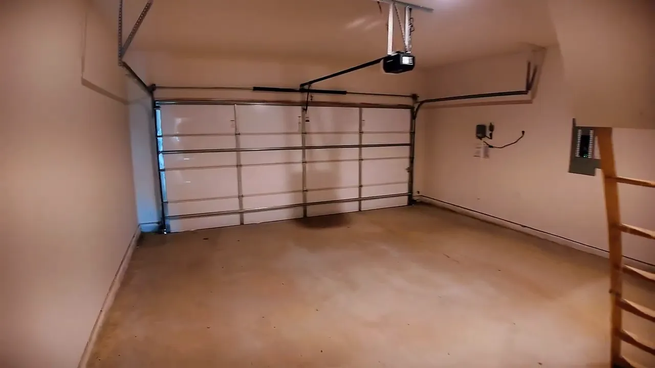 Finished garage interior with textured walls and attic ladder