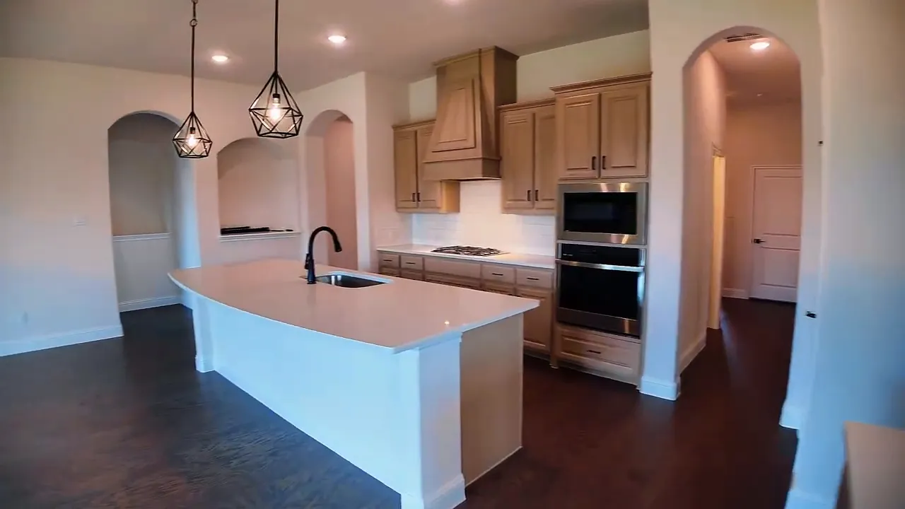 Large white kitchen island with sink pendant lights and wood cabinets